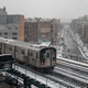 A photo of a subway train driving over a street in The Bronx.